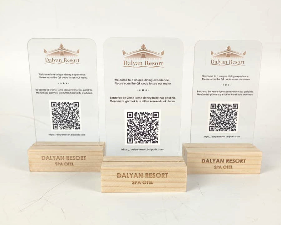 Şık ahşap ayaklı, pleksi gövdeli QR kod standı, masaüstü kullanım için idealdir.