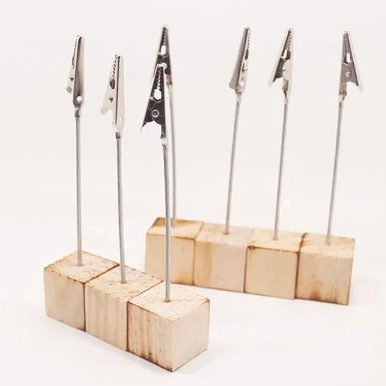 Doğal ahşap zeminli, kıskaç detaylı masaüstü kartlık ve not tutucu ürün görseli.

