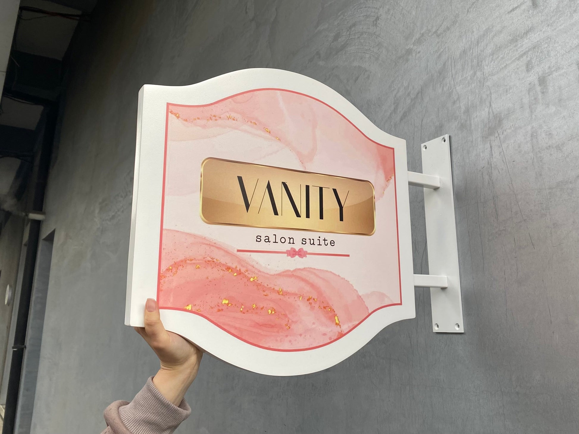 Kıvrımlı kenarlı metal giriş tabelası, dış mekana monte edilmiş, şık tasarımıyla dikkat çekiyor.