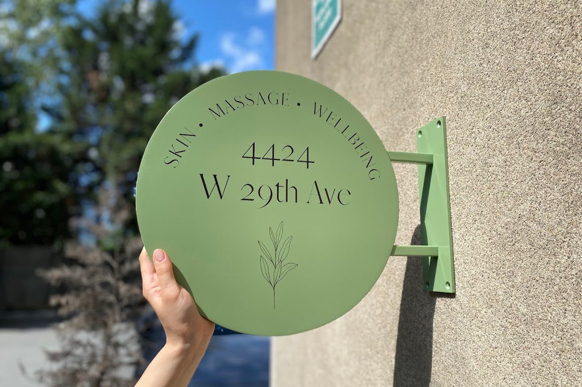 Duvara monte edilmiş yeşil renkli metal giriş tabelası dış mekanda sergileniyor.