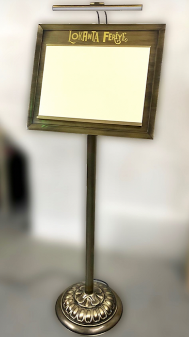 Açık hava kafelerinde kullanılan ışıklı metal menü panosu, dayanıklı yapısıyla dış mekanda da şık bir sunum sunar.