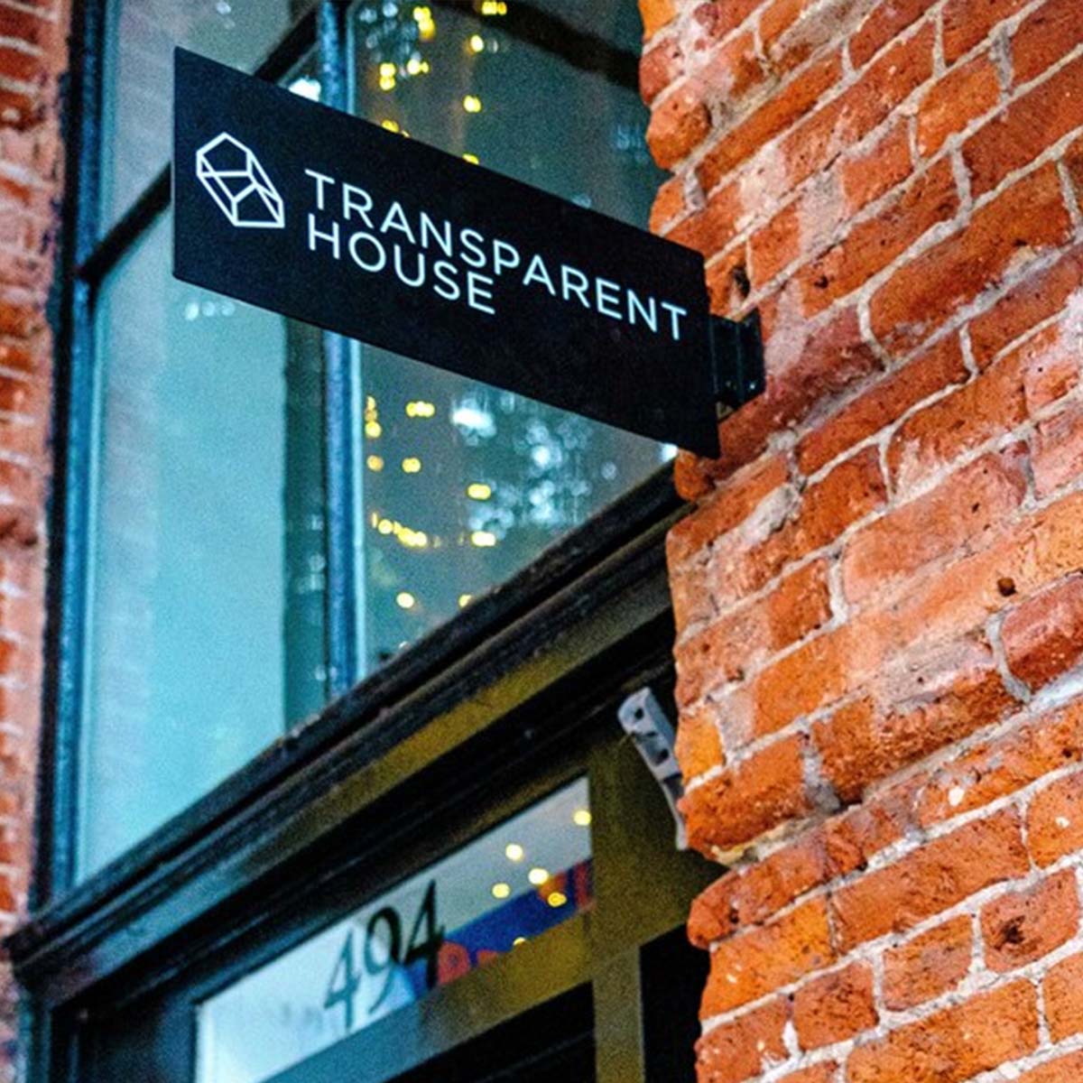 Siyah zemin üzerine beyaz logolu dikdörtgen metal tabela yakın plan çekim.