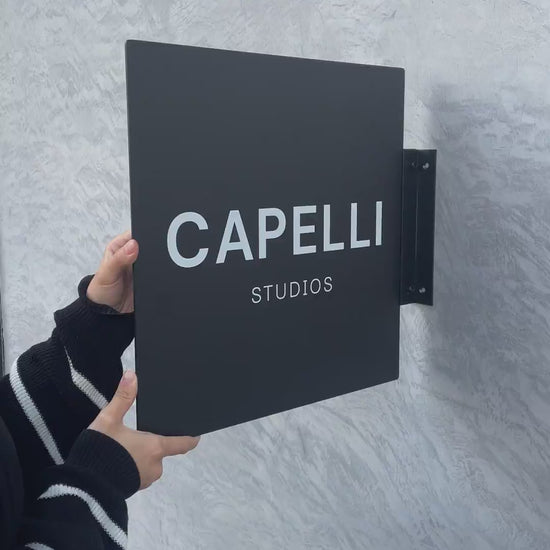 Asma aparatıyla birlikte monte edilen siyah kare tabela.

