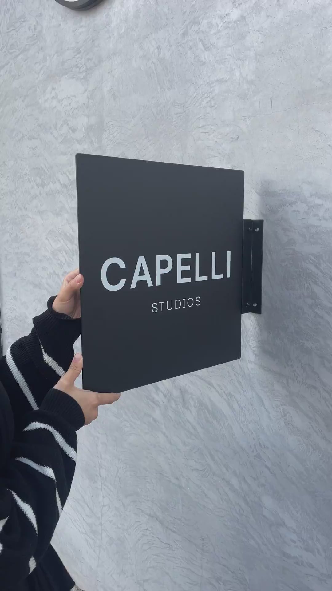 Asma aparatıyla birlikte monte edilen siyah kare tabela.

