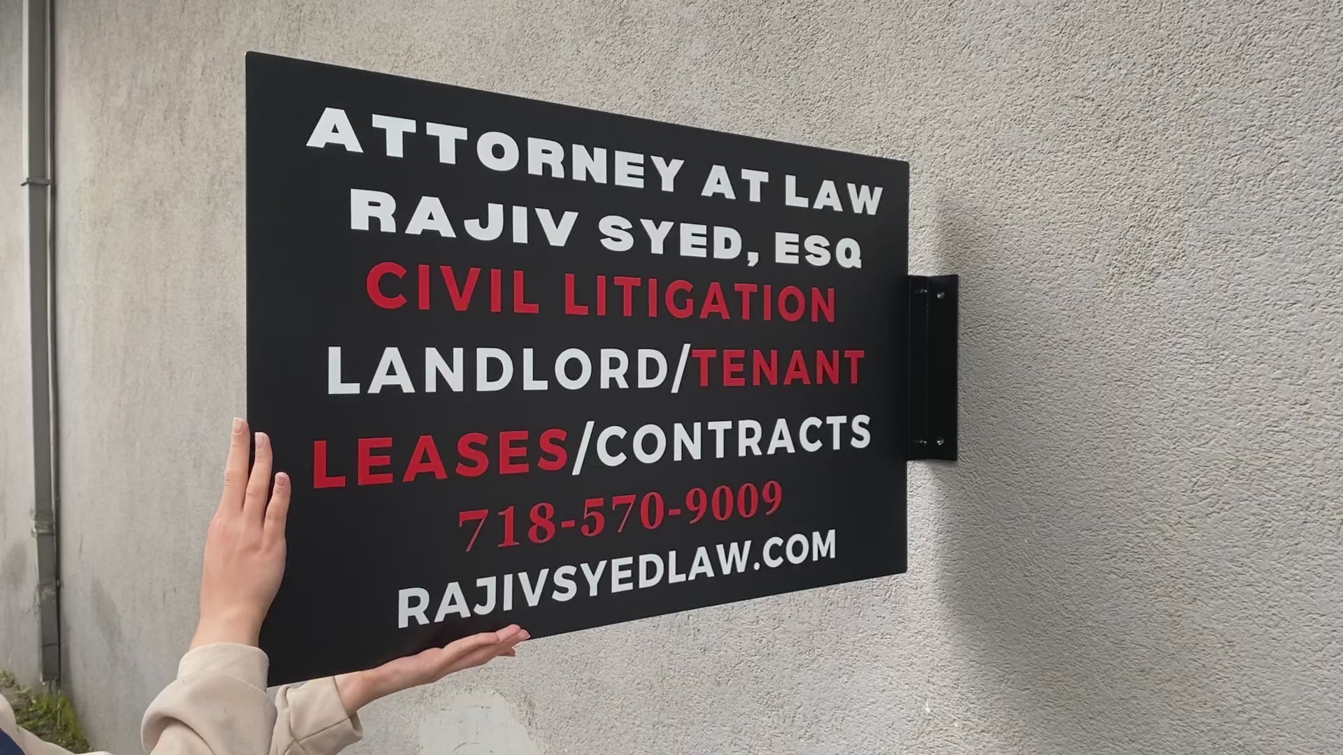 Duvar rengiyle uyum sağlayan mat siyah dikdörtgen tabela örneği.

