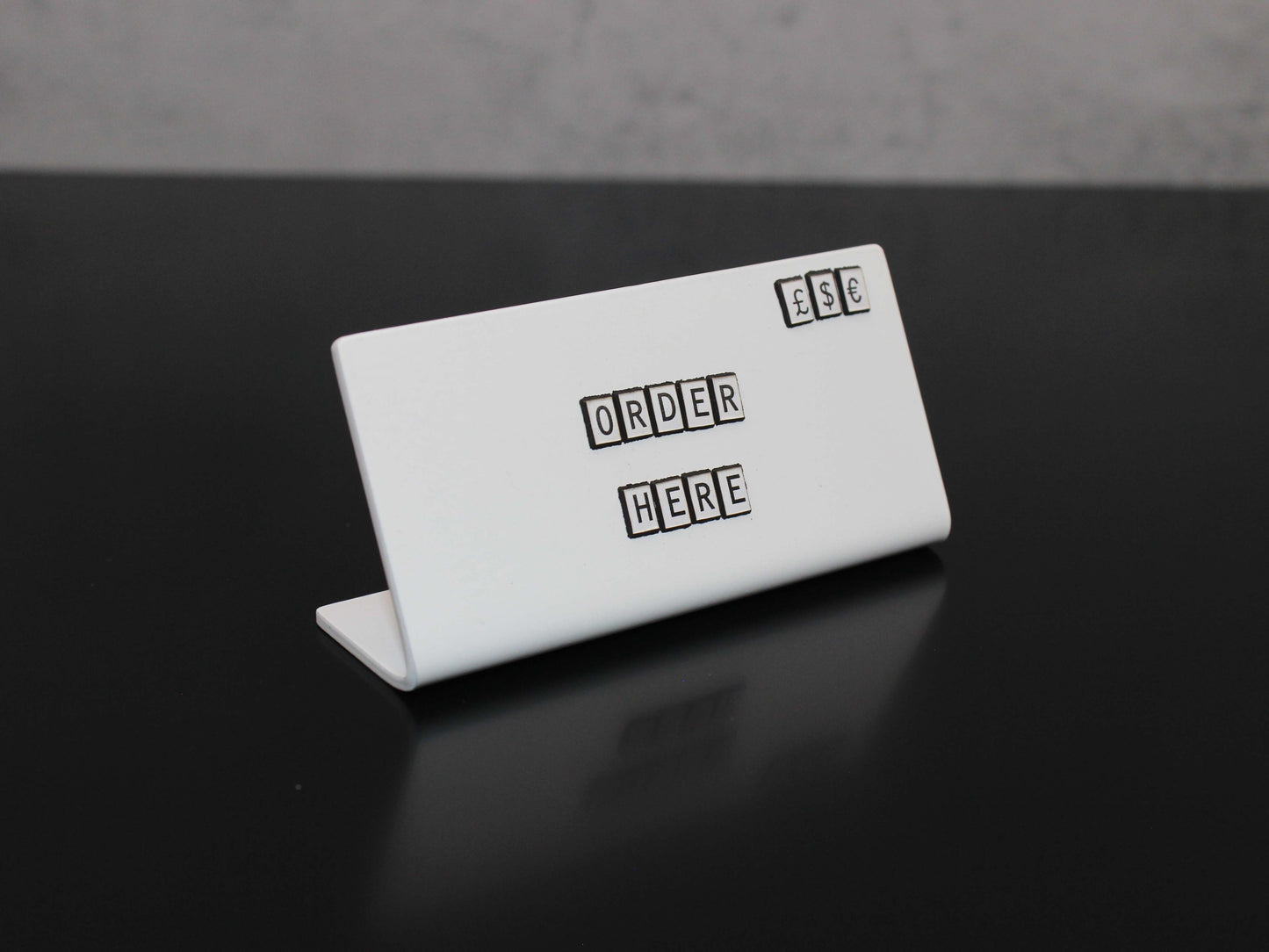 Beyaz harf detaylı metal ürün etiketi.