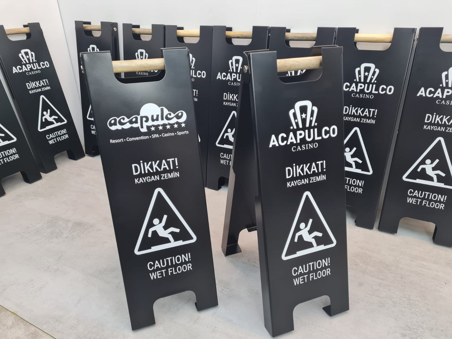 Çift yönlü kullanıma uygun kaygan zemin uyarı tabelası bitkili bir ortamda konumlandırılmış.